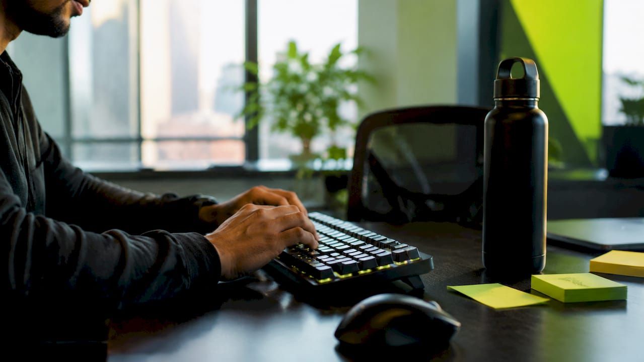 Hands typing code on keyboard in tech office