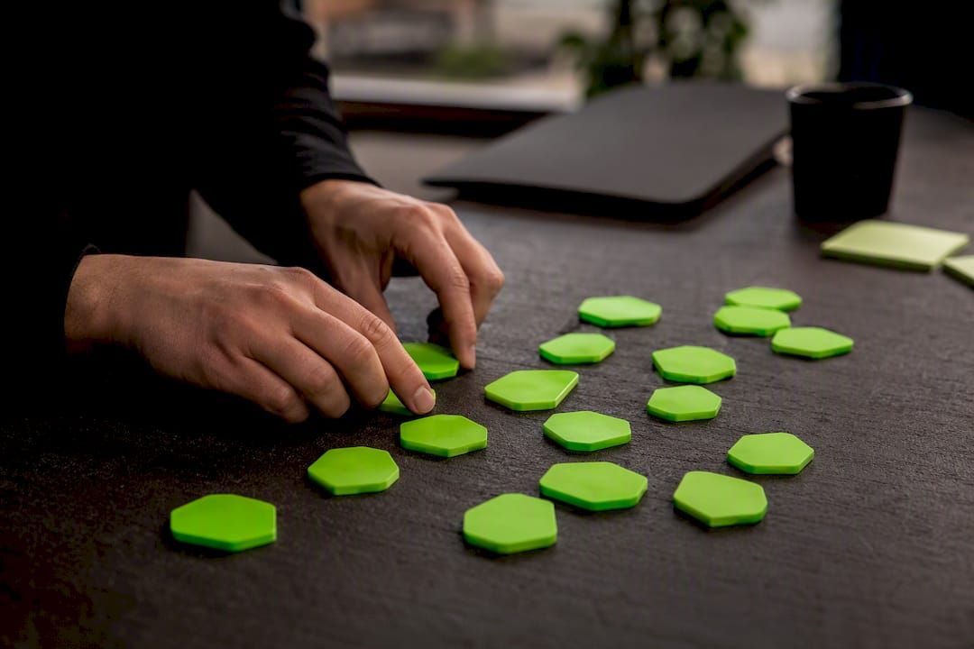 Hands sorting neon-green modular workflow tokens