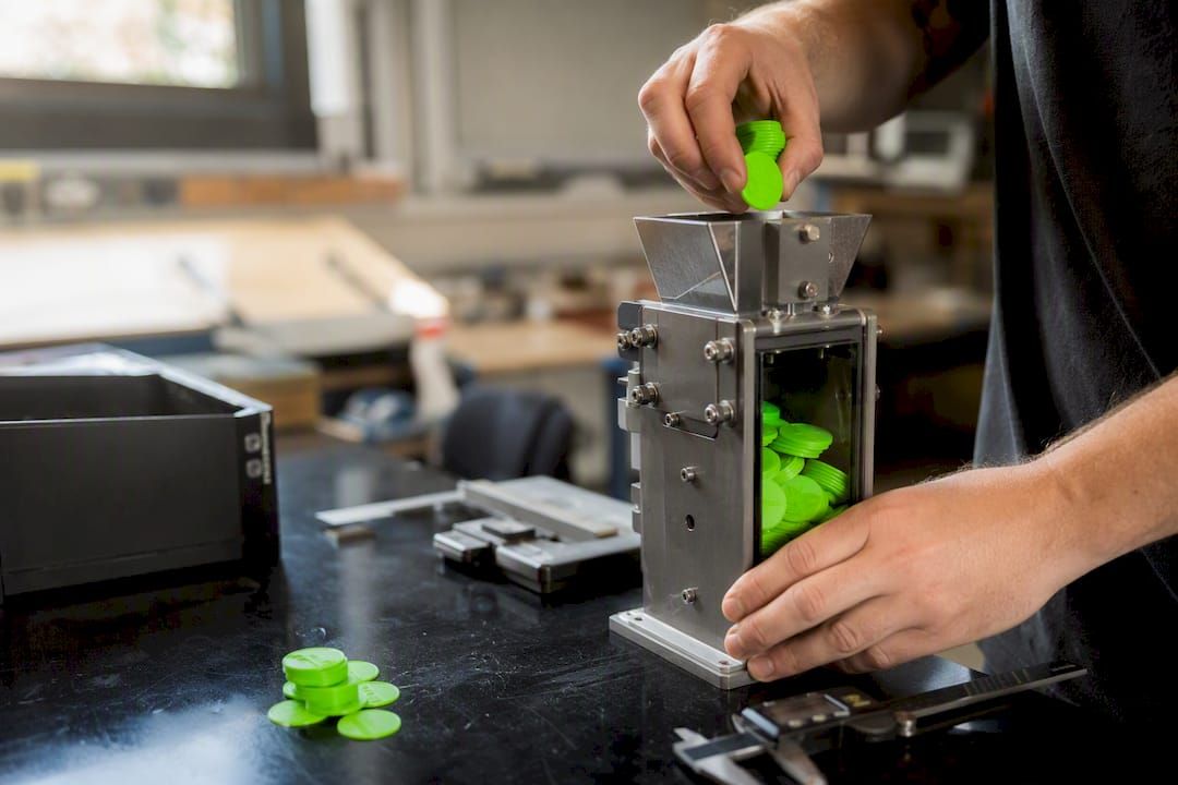 Hands placing tokens into a mechanical bucket model